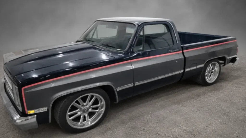 Black Chevrolet squarebody pickup with red side trim photographed after body and paint work.