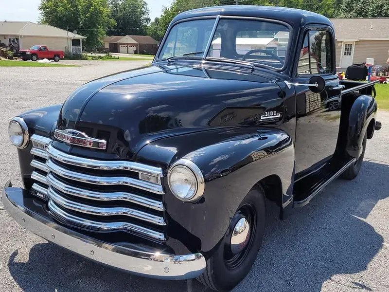 Glossy black classic Chevrolet 3100 pickup with restored bodywork and chrome trim at Pettie's Auto Body.